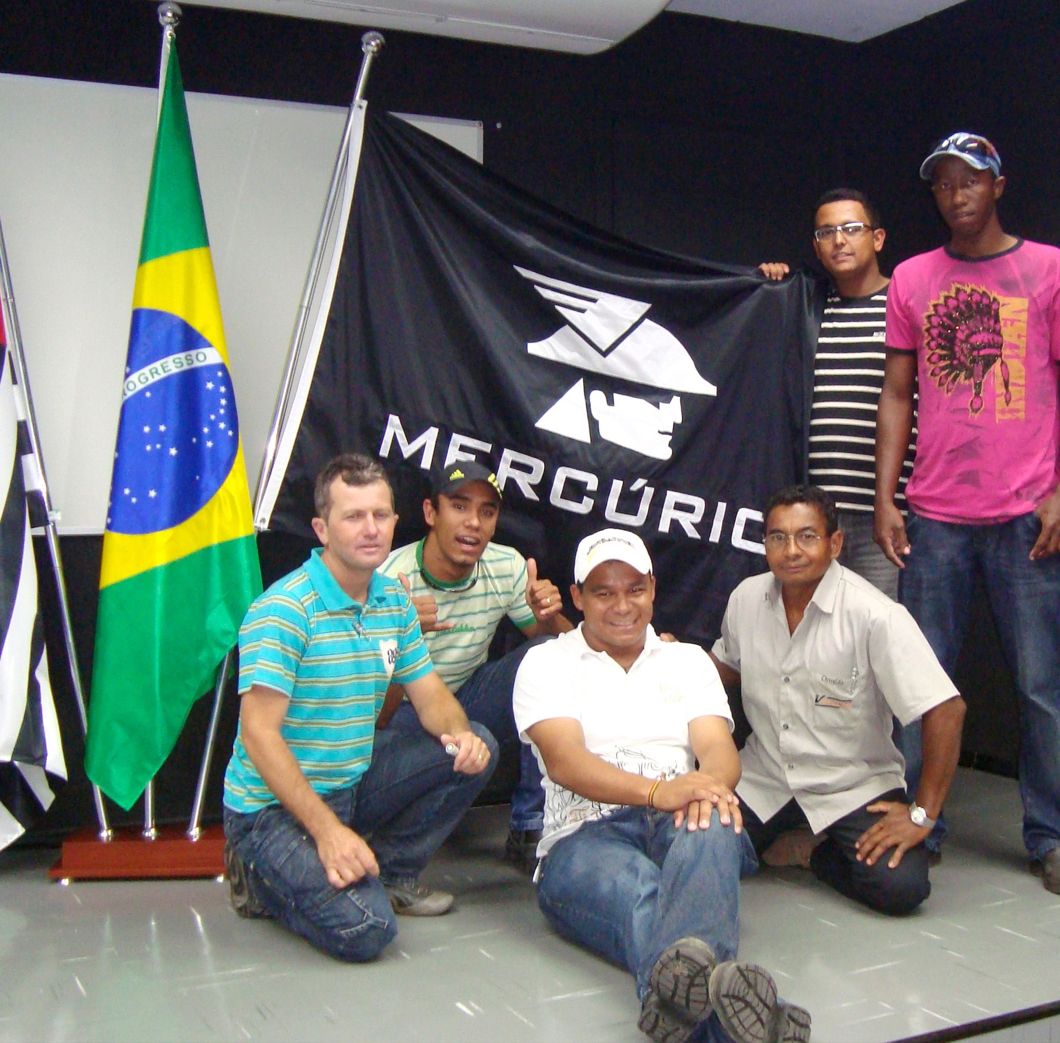 Grupo reunido em frente à bandeira da Mercúrio durante a visita